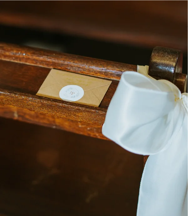 Envelope com lenço colocado no banco da igreja para o casamento J&P.
